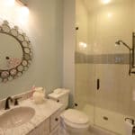 bathroom with circle mirror with shower